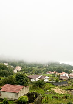 A rural village with scattered houses surrounded by lush green vegetation and hills. photo