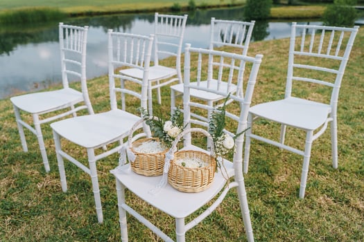 Setup white chairs on grass at wedding with wedding flowers in basket.Garden wedding decoration in vanue. photo