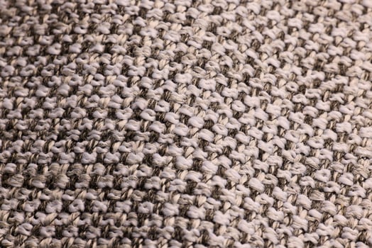 A closeup of a textured beige knitted fabric highlights its intricate detail and craftsmanship photo
