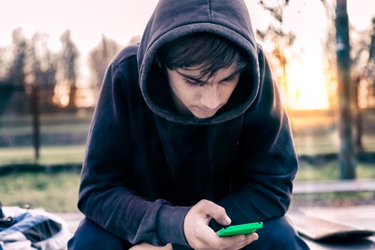 sitting young adult skateboarder writes a message on smart phone photo