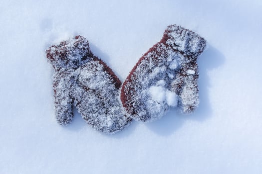 Warm brown child's mittens on snow surface. photo