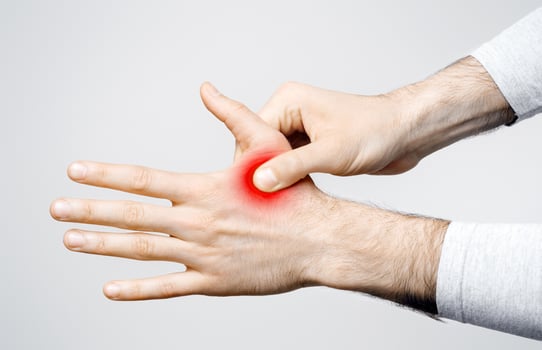 Inflammation in muscles and joints. Man holds to highlighted red hand isolated on gray background, studio shot photo