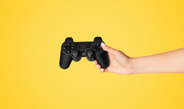 Cropped view of young woman holding game joystick over pink background, closeup. Panorama photo