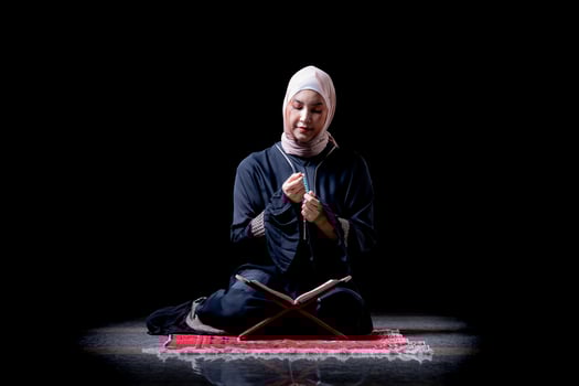The image of an Asian Muslim woman in the Islamic religion in hijab in cream color. reading the Quran and having a happy smiling face Staying in a beautiful mosque out of respect for God. photo