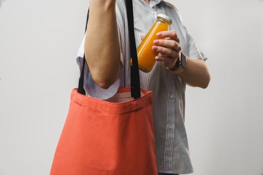 Cropped woman holding fabric shopping bag and juice bottle, studio shot photo