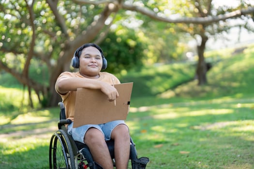 Asian Boy in Wheelchair Enjoying Art in Nature, Listening to Music photo