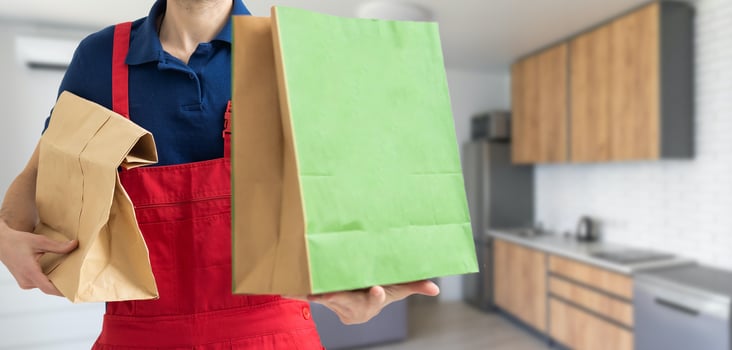 box with fast food being carried by delivery man in uniform for one of clients photo