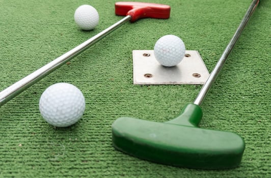 Mini golf. A club and a white ball on a golf course. photo