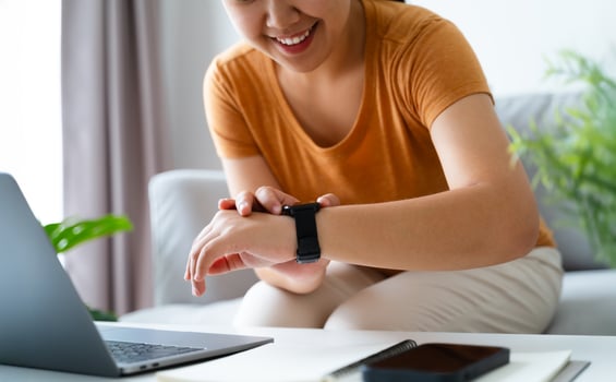 Happy young woman is using smartwatch on her wrist to check health data, notifications, set alarm. photo