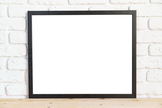 Photo frames on floor over white brick wall
