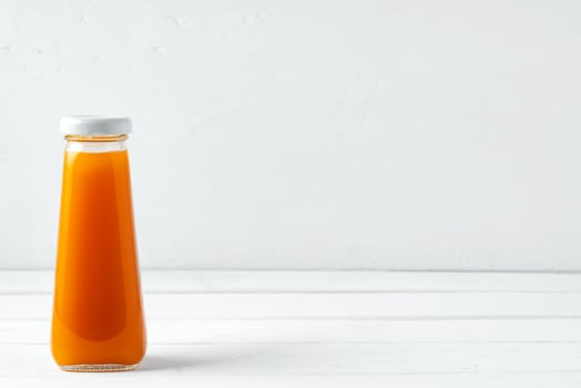 Small glass bottle of fresh juice on white background photo