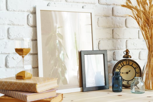 Vase with ears of wheat and photo frames against brick wall
