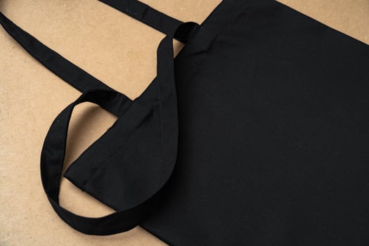 Black textile shopping bag on beige background flat lay photo