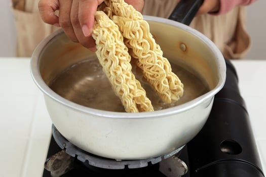 Close Up Female Hand Boiling Dried Instant Noodle on Pan photo