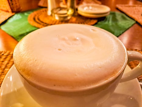 White offee cup and hot cappuccino on wooden table blurred background.Copy space photo