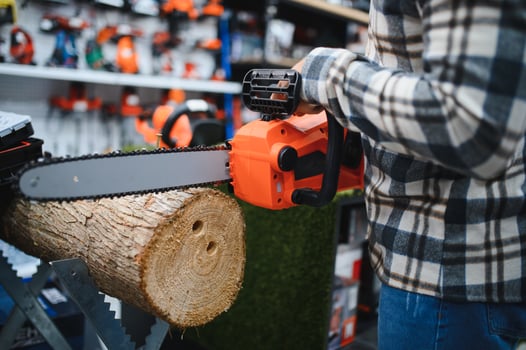 Male worker choosing modern electric chain saw photo