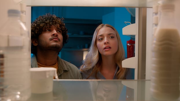 Point of view POV inside refrigerator Caucasian girl woman girlfriend wife and Arabian man Indian guy boyfriend husband multiracial couple at night evening open empty fridge at kitchen unhappy sad photo