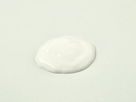 White lotion cream drop texture isolated on horizontal white background. photo