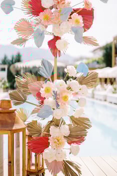 Wedding arch stand with colorful flowers near wooden candle lamp on the shore of the pool photo