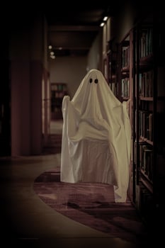 Child dressed as a white ghost in a library room photo