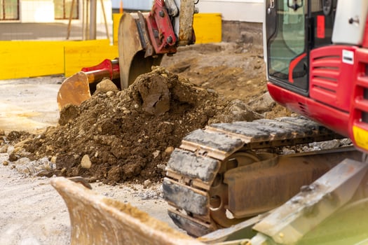 Excavator bucket collects soil and old asphalt at a construction site photo