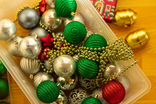 Multi-colored Christmas tree toys and garlands in a plastic box on the floor photo