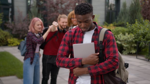 Stressed African American school guy male student bullied man suffer with racism discrimination bullying multiracial students classmates mock humiliate bully mockery at college university outdoors photo