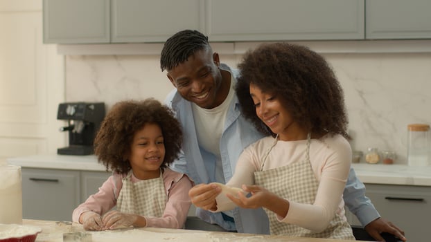 Happy African American family at home kitchen woman man and little girl father cuddling hugging child kid daughter mother show dough flour cooking cookies cook baking pastry together talking insurance photo