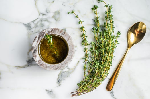 Flavoring extra virgin olive oil with thyme and rosemary. Top view. White background photo
