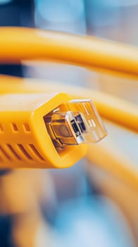 Yellow industrial tubing with metal connector showcased in detail in a manufacturing facility photo