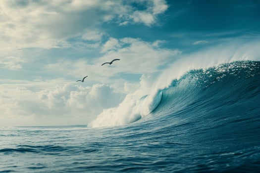 Waves crashing under a bright sky with seagulls soaring above the ocean surface photo