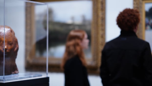 The young people watching the paintings in the museum with the blurred shot photo