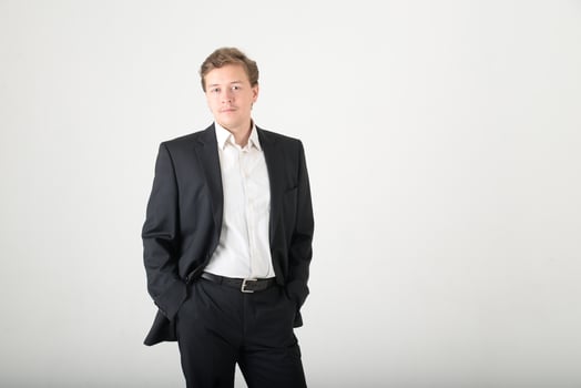 A young man wearing a black business suit with a white shirt on a white background with copy space. Business success concept photo