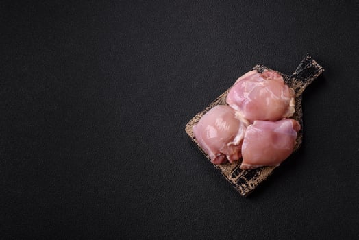 Fresh raw chicken thigh fillets with salt, spices and herbs photo