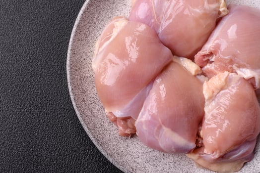 Fresh raw chicken thigh fillets with salt, spices and herbs photo