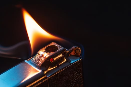 Janalyso Lighting a Zippo Close-Up on Dark Black Background. Concept of Handheld Firestarters, Vintage Collectibles, and Urban Aesthetics photo