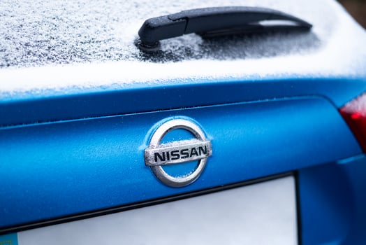 Kyiv, Ukraine. 6 December, 2024. Close-up of a blue Nissan car covered in snow, featuring the logo on the trunk with frost and winter details. photo