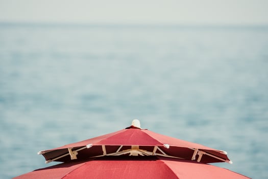 Red Beach Umbrella on the Background of the Blue Sea Ocean. Beach Landscape. Summer travel and holidays concept. photo