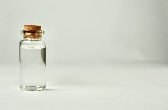 Transparent glass vial bottle container with brown cork stopper lid isolated on horizontal empty copy spaced white background. photo