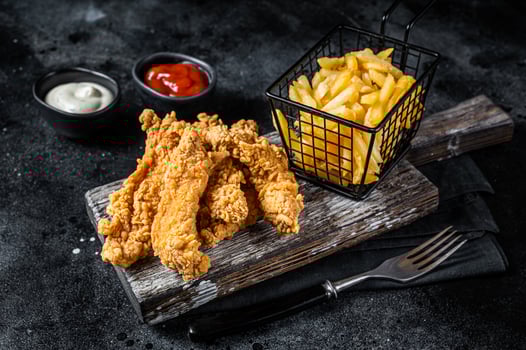 Chicken breast strips with French Fries and Ketchup. Black background. Top view photo