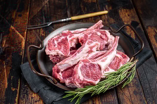 Raw lamb mutton chop steaks, fresh meat cutlets on butcher table. Black background. Top view photo