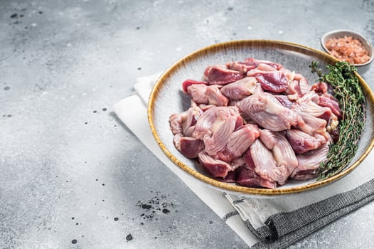 Raw chicken stomachs offals in a plate with herbs. Gray background. Top view. Copy space photo