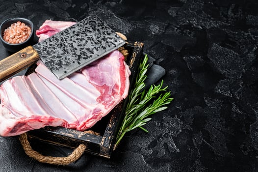 Butcher table with Rack of lamb, raw mutton ribs with meat cleaver. Black background. Top view. Copy space photo
