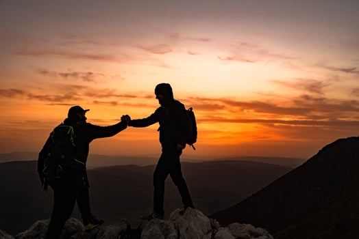 Hiking team people helping each other friend giving a helping hand while climbing up on the mountain rock adventure travel concept of support trust teamwork business success. photo