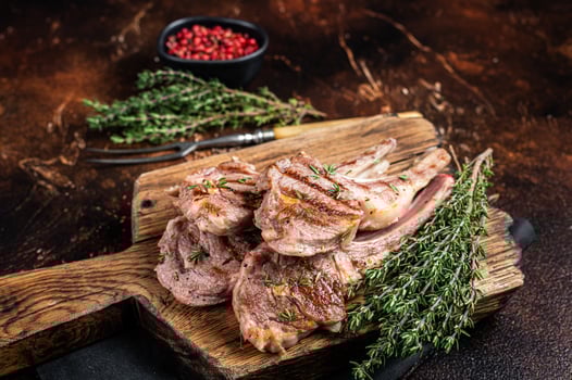 Grilled New Zealand Lamb Chops, mutton cutlets on wooden board. Dark background. Top view photo