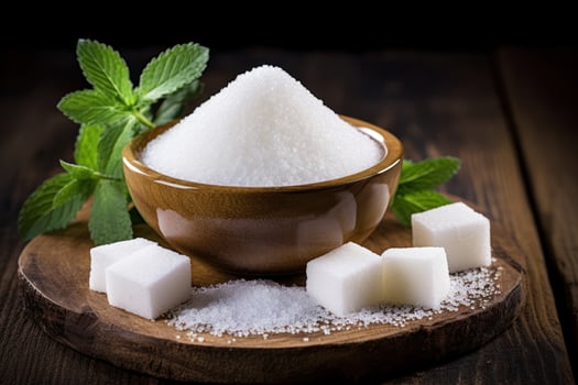 Refined white sugar in a wooden bowl with fresh mint leaves photo