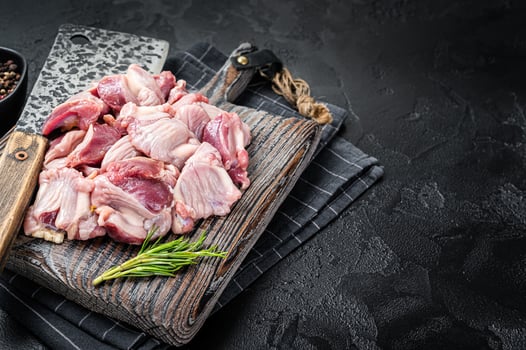 Raw chicken stomachs, giblets gizzards on a butcher board with meat cleaver. Black background. Top view. Copy space photo