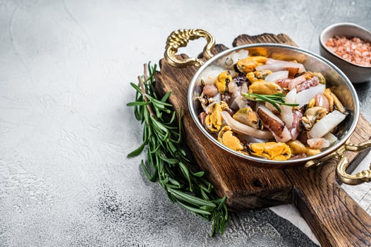 Mixed Seafood, variation of fresh mussels, clams, squid, octopus, shrimps and prawn in a skillet. White background. Top view. Copy space photo