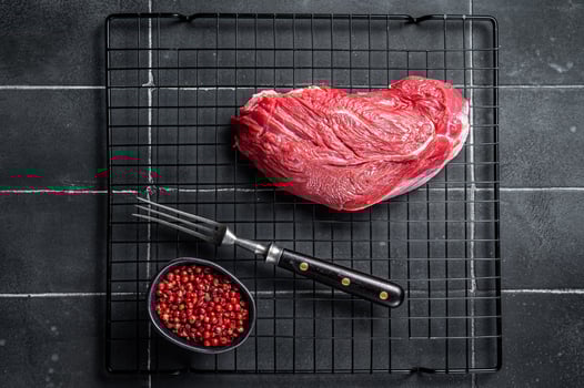 Raw beef meat piece for grilling with spices. Black background. Top view photo