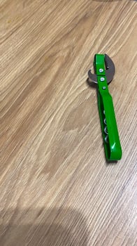 A green bottle opener sitting on top of a wooden table photo